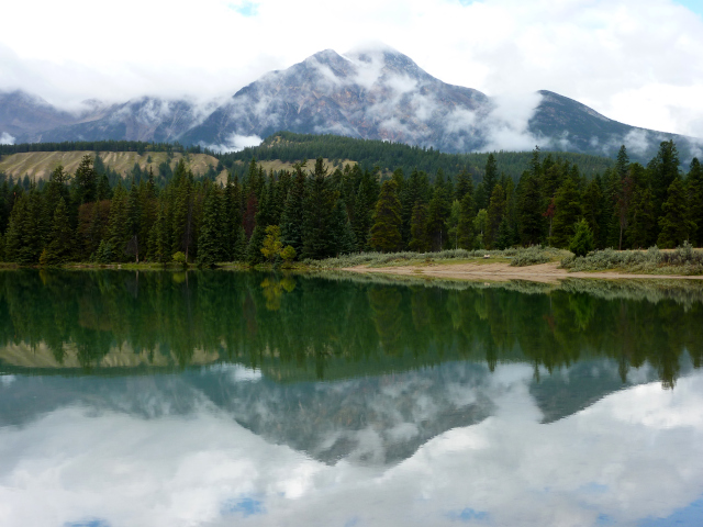 Photo of Pyramid Mt. in Jasper. The mountain is beautifully reflected in a small lake. 